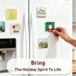 A hand is attaching a square holiday magnet to a white refrigerator door, with other decorative fridge magnets visible around it. The scene includes a text overlay that reads 'Bring The Holiday Spirit To Life.