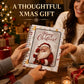 A spiral-bound notebook with a festive Christmas cover featuring Santa Claus and the text 'Merry Christmas!' is held by two people in a warmly lit holiday setting. Large text at the top reads 'A THOUGHTFUL XMAS GIFT'.