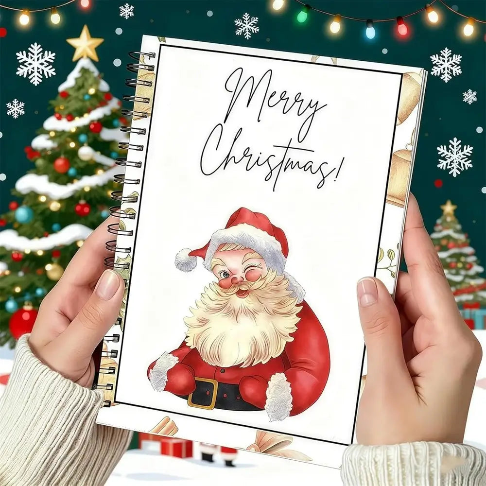 A person holds a spiral-bound notebook with a festive Christmas cover design featuring an illustration of Santa Claus and the words 'Merry Christmas!' in script. The background shows a decorated Christmas tree, snowflakes, and warm string lights.