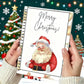 A person holds a spiral-bound notebook with a festive Christmas cover design featuring an illustration of Santa Claus and the words 'Merry Christmas!' in script. The background shows a decorated Christmas tree, snowflakes, and warm string lights.