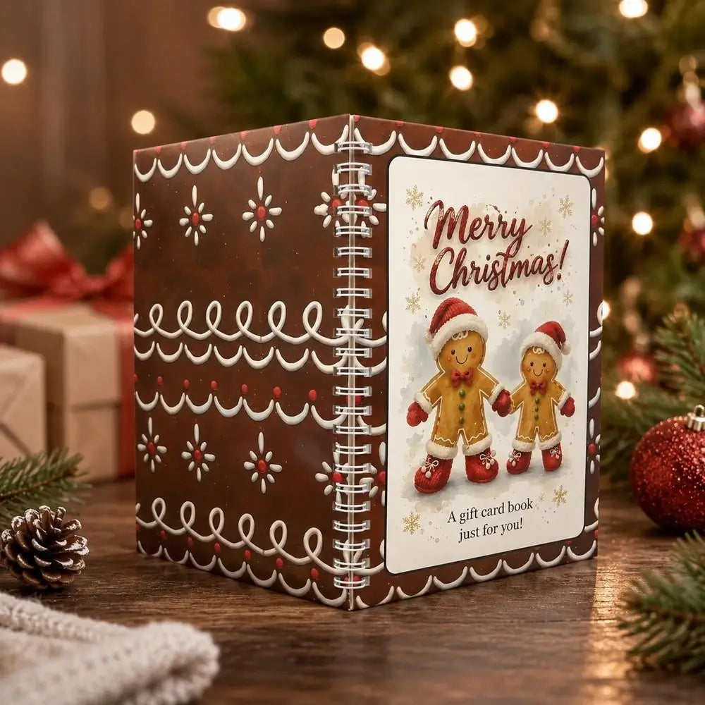 A Christmas-themed gift card book standing on a wooden table, decorated with a gingerbread-style pattern in brown, white, and red. The front cover features a white panel with the text 'Merry Christmas! A gift card book just for you!' and an illustration of two gingerbread men.
