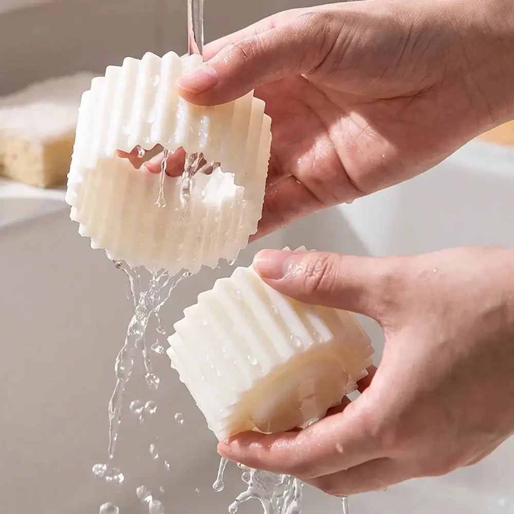 Two hands holding white double-ended pastry mold under running water in a sink.