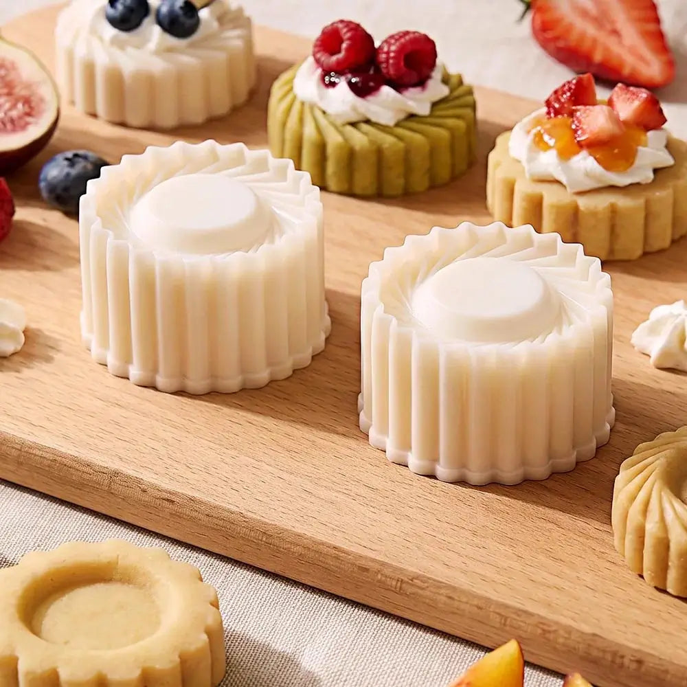 Two round scalloped pastry molds, shown on a wooden board with other pastries and fresh berries around them.