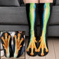 Green and blue frog leg socks with orange webbed toes worn on legs before a gray sofa