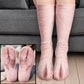 Soft pink pig foot socks with split toes worn on legs before a gray sofa