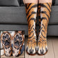 Orange tiger striped paw socks worn on legs before a gray sofa with a closeup of padded paw soles
