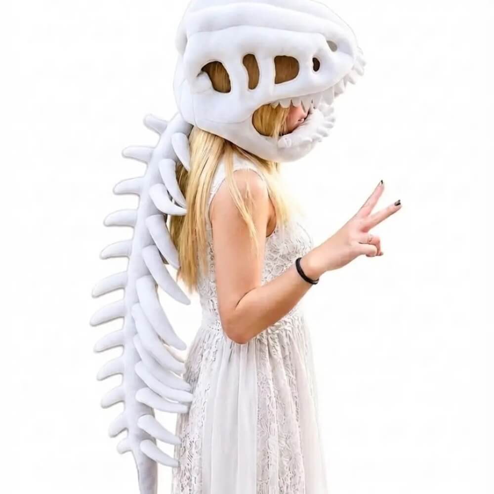 A woman wearing a white dinosaur skeleton costume with a large skull headpiece and spine, posing in a white lace dress against a plain white background.
