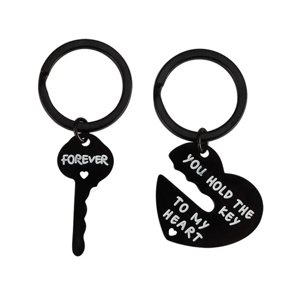 Black key and heart-shaped keychain with engraved text on a white background
