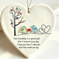 A heart-shaped ceramic ornament with a hanging loop, featuring a black tree with colorful heart-shaped leaves, two small birds facing each other with a red heart between them, and a black outlined double heart. Below the illustration is a printed friendship message.