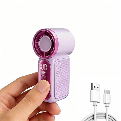 A hand holding a small handheld fan cooler in light purple and magenta, with a USB charging cable shown at the lower right on a white background.