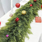 Decorative green garland with red and gold ornaments on a white surface