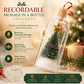 A holiday-themed product listing graphic for a Recordable Message in a Bottle Ornament. The main subject is a clear glass bottle ornament with a cork stopper, red ribbon loop, and a small decorated Christmas tree inside with a gold star.