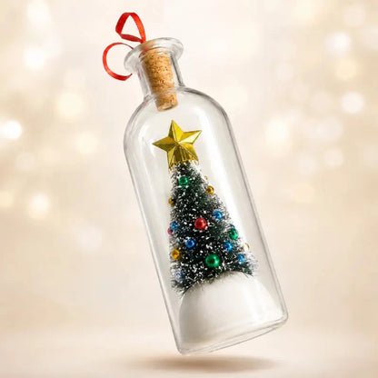 A clear glass bottle ornament with a cork stopper and red ribbon, containing a miniature Christmas tree with colorful ornaments, a gold star topper, and a white snowy base, shown against a warm blurred bokeh background.