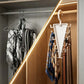 A white triangular wall-mounted organizer hook hanging on a wooden closet door, holding multiple neckties and scarves. The closet interior with warm LED lighting is visible in the background.