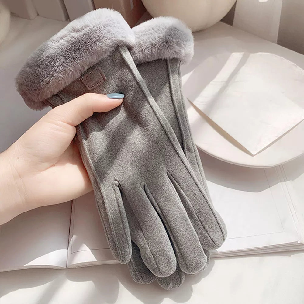 Gray glove with fur trim held by a hand on a light surface