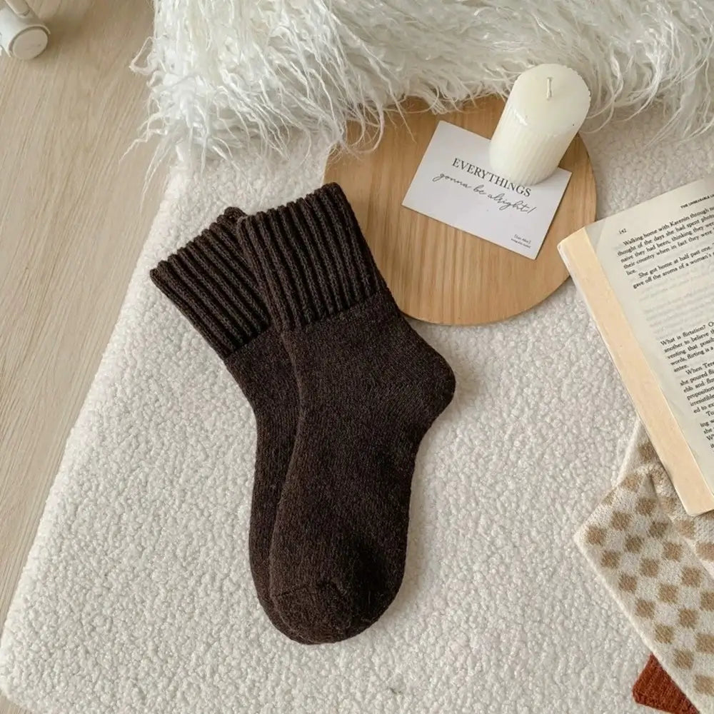 Brown sock on a textured surface with a candle and book in the background